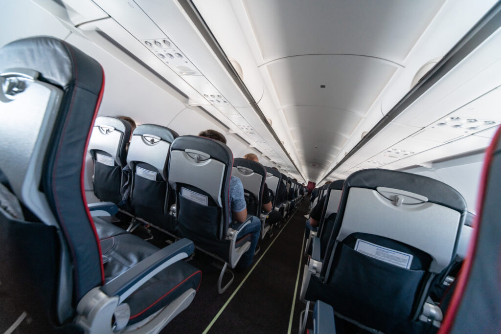 Cheap flights. Airplane cabin seats with passengers. Economy class of new cheapest low-cost airlines. Travel trip to another country. Turbulence in flight.