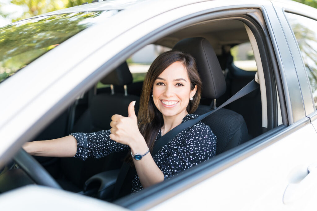 car insurance. Portrait of smiling attractive woman showing thumbs up while driving new car